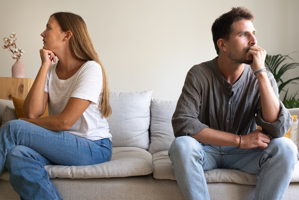 Couple sitting apart on a sofa, thinking about separation