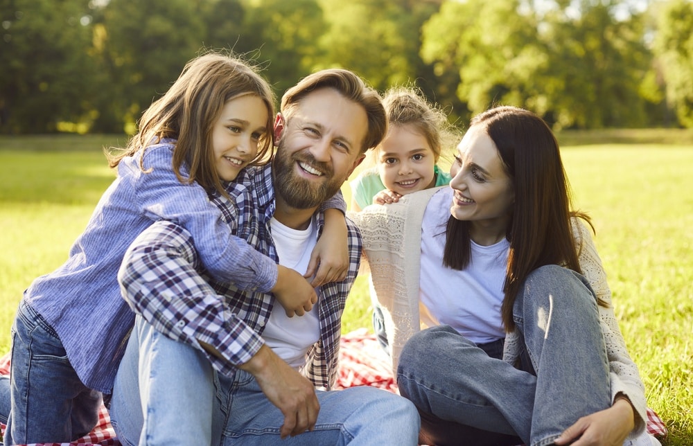Parents and two children together on a picnic blanket in a park